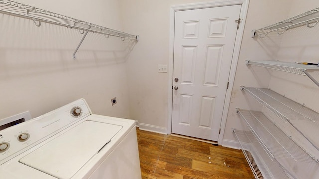 clothes washing area with laundry area, washer / dryer, baseboards, and wood finished floors