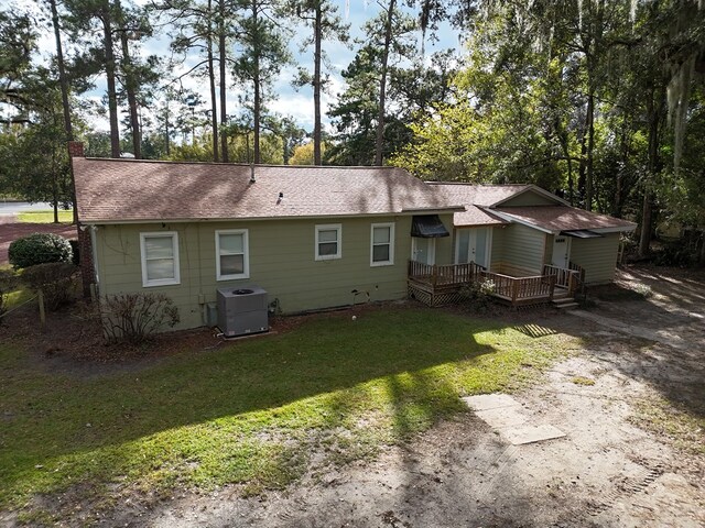 back of house with cooling unit and a lawn