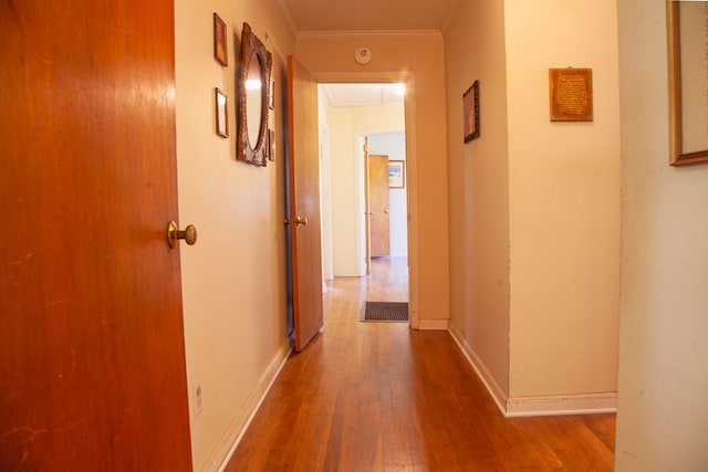 corridor featuring baseboards, attic access, crown molding, and wood finished floors