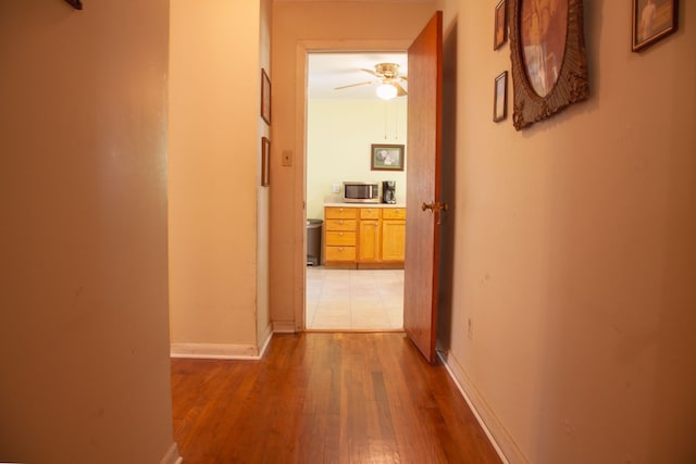 hallway featuring light wood-style floors and baseboards