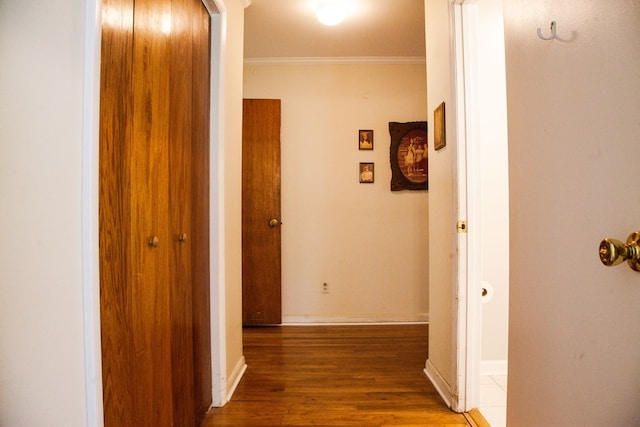 corridor with wood finished floors, baseboards, and ornamental molding