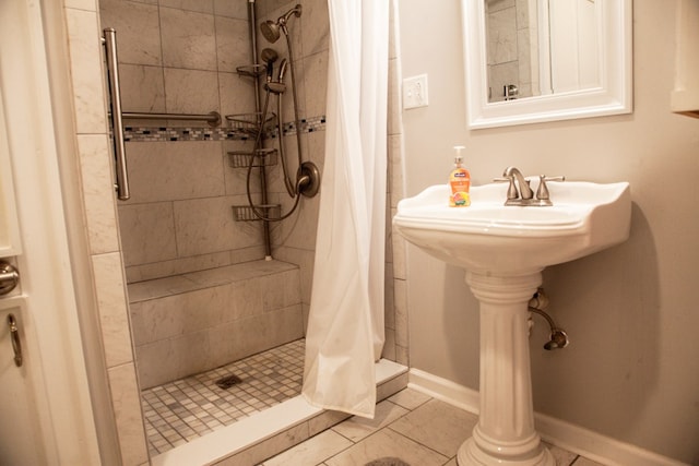 bathroom with a stall shower, baseboards, and tile patterned flooring