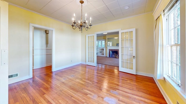 unfurnished dining area featuring french doors, ornamental molding, hardwood / wood-style floors, and a brick fireplace