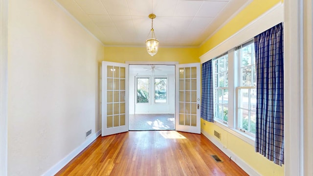 entryway with plenty of natural light, ornamental molding, french doors, and light wood-type flooring