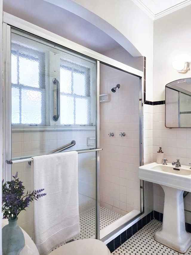 bathroom with sink, crown molding, tile walls, toilet, and walk in shower