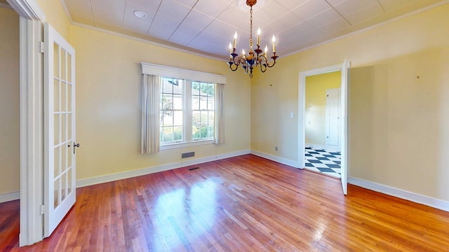 spare room with a notable chandelier, hardwood / wood-style flooring, and ornamental molding