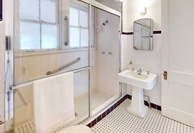 bathroom featuring tile patterned flooring, tile walls, and a shower with shower door