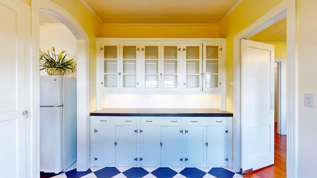 kitchen with white cabinetry, crown molding, and white fridge