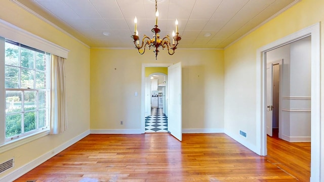 empty room featuring crown molding, a chandelier, and light wood-type flooring