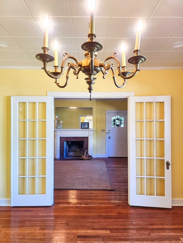 unfurnished living room featuring crown molding, dark hardwood / wood-style floors, a notable chandelier, and a fireplace