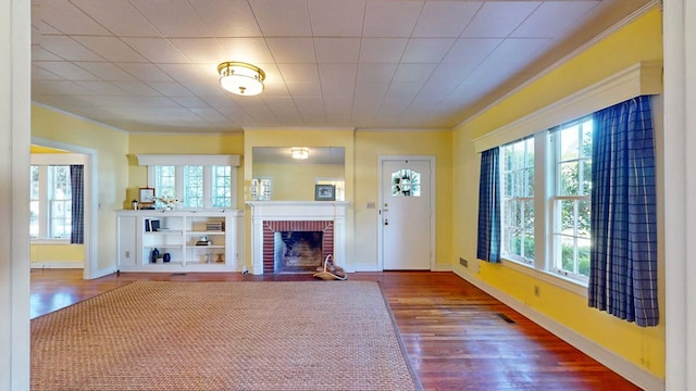 unfurnished living room with ornamental molding, a fireplace, hardwood / wood-style floors, and a wealth of natural light