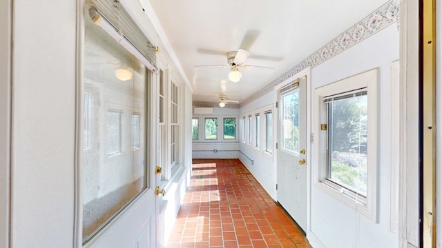 unfurnished sunroom featuring ceiling fan