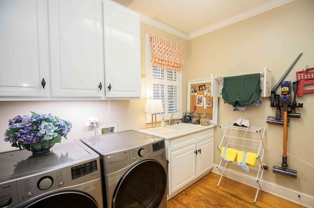 clothes washing area with sink, cabinets, ornamental molding, washer and clothes dryer, and light wood-type flooring