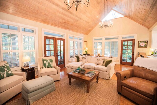 living room with french doors, a notable chandelier, light hardwood / wood-style flooring, and wooden ceiling