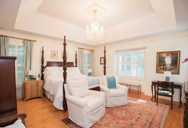 bedroom featuring crown molding, hardwood / wood-style floors, a tray ceiling, and a chandelier