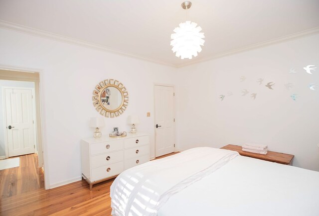 bedroom with an inviting chandelier, light hardwood / wood-style flooring, and ornamental molding