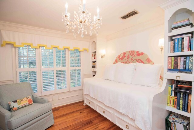 bedroom with hardwood / wood-style floors, ornamental molding, and a chandelier