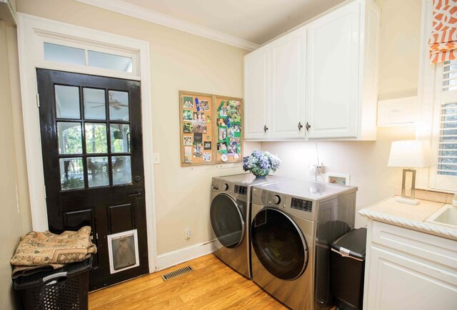 laundry room with sink, crown molding, light hardwood / wood-style flooring, cabinets, and washing machine and clothes dryer