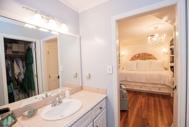 bathroom with hardwood / wood-style flooring, vanity, crown molding, and a chandelier