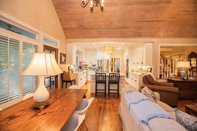 living room with light hardwood / wood-style flooring, wood ceiling, vaulted ceiling, and a chandelier