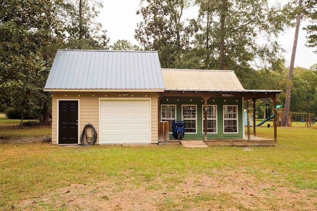 view of outbuilding featuring a garage, a lawn, and a playground