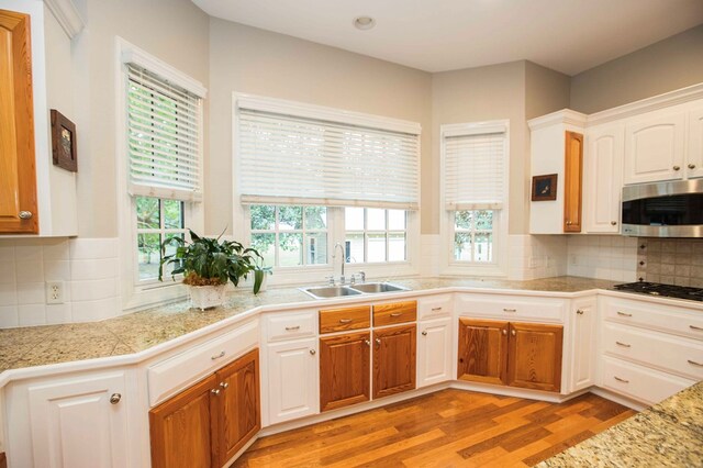 kitchen featuring sink, light hardwood / wood-style flooring, appliances with stainless steel finishes, a healthy amount of sunlight, and white cabinets