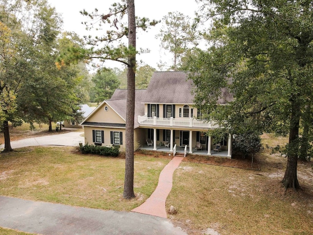 colonial house featuring a front lawn and a patio area