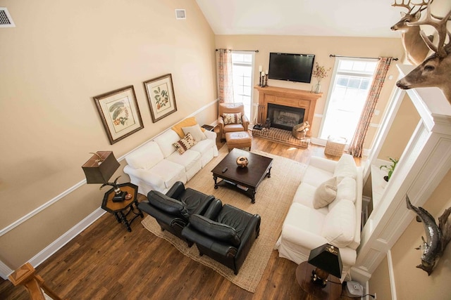 living room with lofted ceiling, hardwood / wood-style floors, plenty of natural light, and a brick fireplace