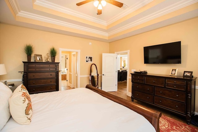 bedroom featuring ornamental molding, wood-type flooring, connected bathroom, and a raised ceiling