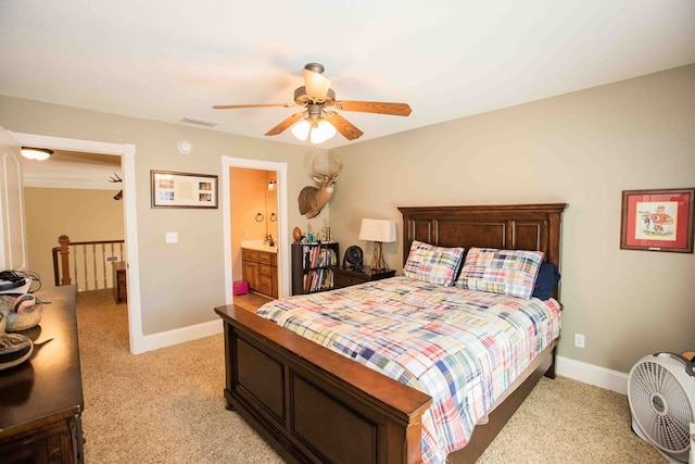 bedroom with ensuite bathroom, light carpet, and ceiling fan