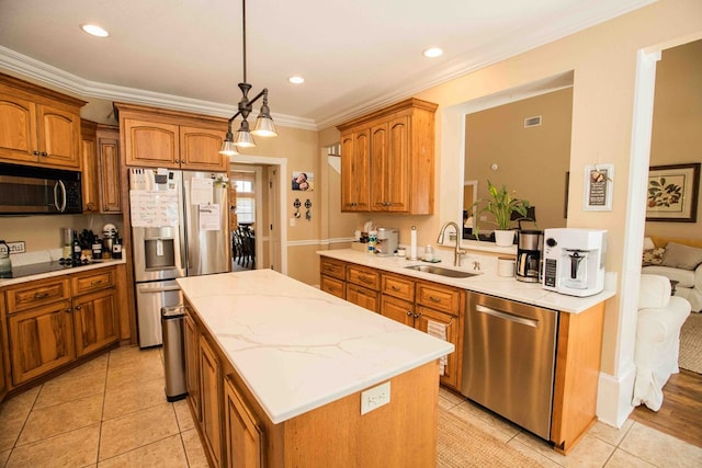 kitchen featuring a kitchen island, appliances with stainless steel finishes, pendant lighting, sink, and ornamental molding