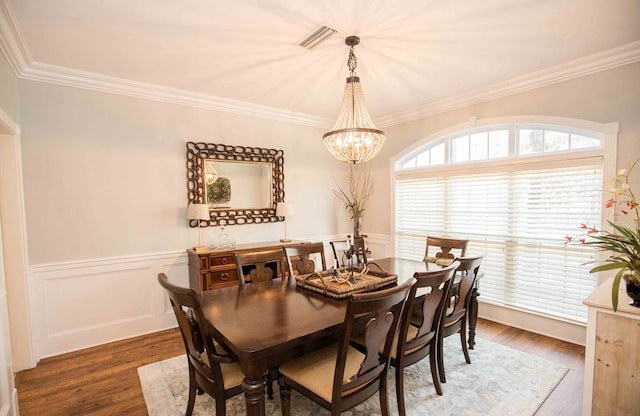 dining area with an inviting chandelier, ornamental molding, and dark hardwood / wood-style flooring