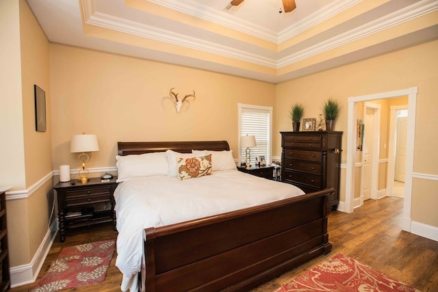 bedroom featuring crown molding, dark wood-type flooring, a raised ceiling, and ceiling fan