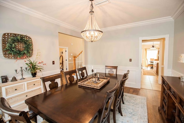 dining room with hardwood / wood-style flooring, ornamental molding, and an inviting chandelier