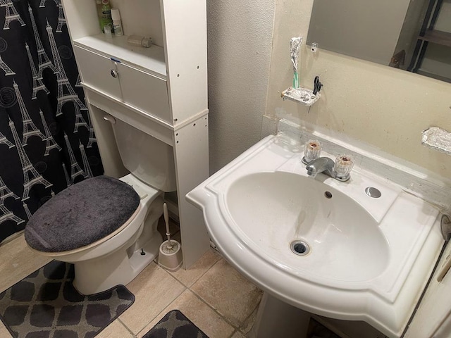 bathroom featuring toilet, tile patterned flooring, and a sink