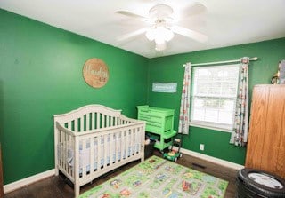 bedroom featuring a nursery area and ceiling fan