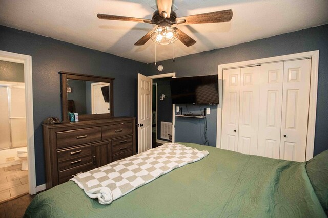 bedroom featuring hardwood / wood-style flooring, ensuite bath, ceiling fan, and a closet