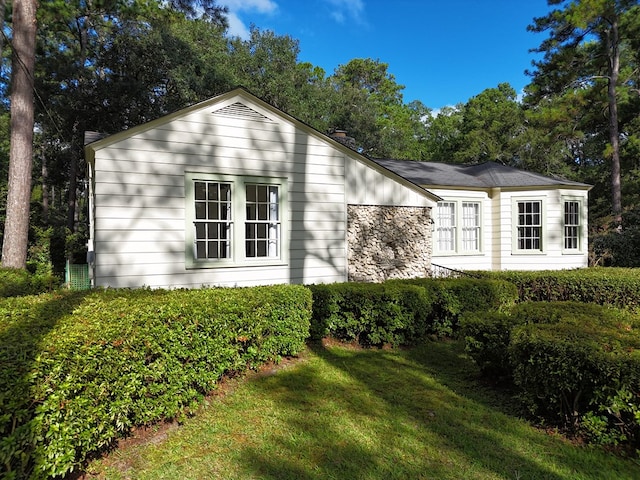 view of property exterior with stone siding and a yard