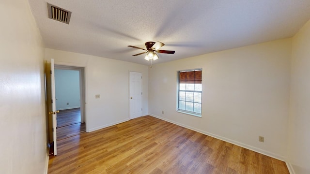 unfurnished room with ceiling fan, a textured ceiling, and light wood-type flooring