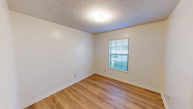 spare room featuring light hardwood / wood-style floors and a textured ceiling