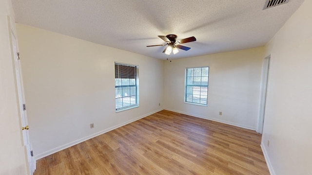 empty room featuring ceiling fan, light hardwood / wood-style flooring, and a textured ceiling