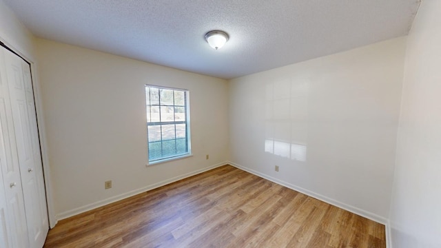 unfurnished bedroom featuring light hardwood / wood-style floors, a closet, and a textured ceiling