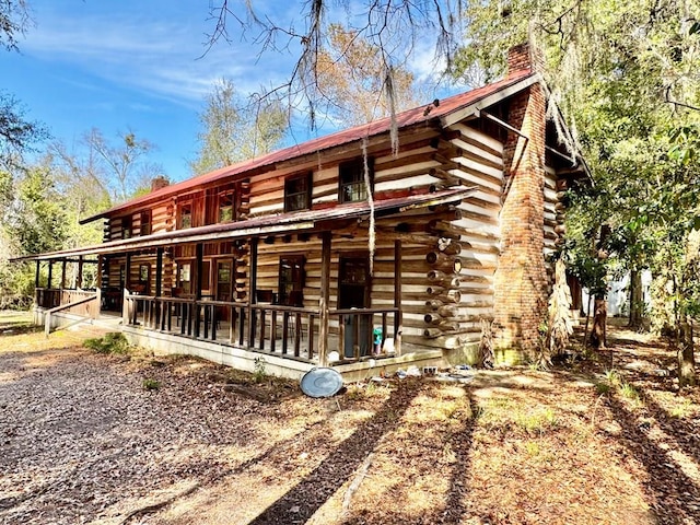 back of house with a chimney and log siding