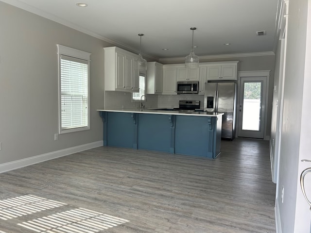 kitchen with a kitchen bar, decorative light fixtures, kitchen peninsula, stainless steel appliances, and white cabinets