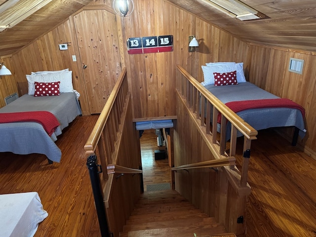 bedroom featuring visible vents, wooden walls, wood finished floors, and vaulted ceiling