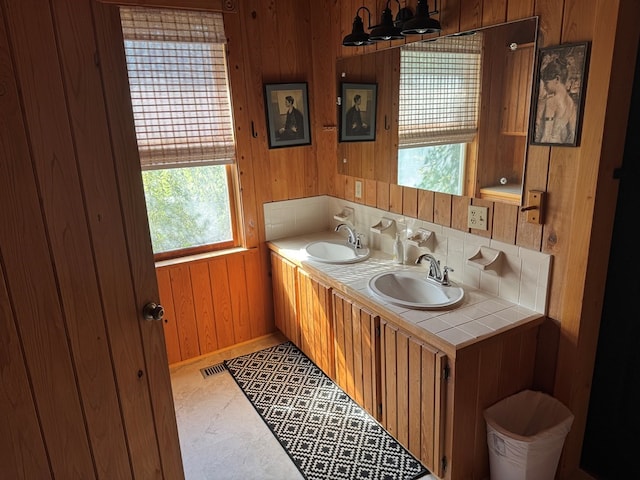 bathroom with double vanity, wood walls, and a sink