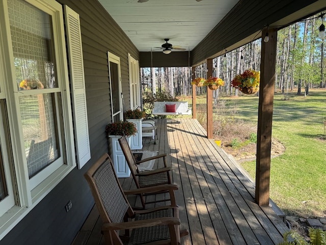 wooden deck featuring a yard and a ceiling fan