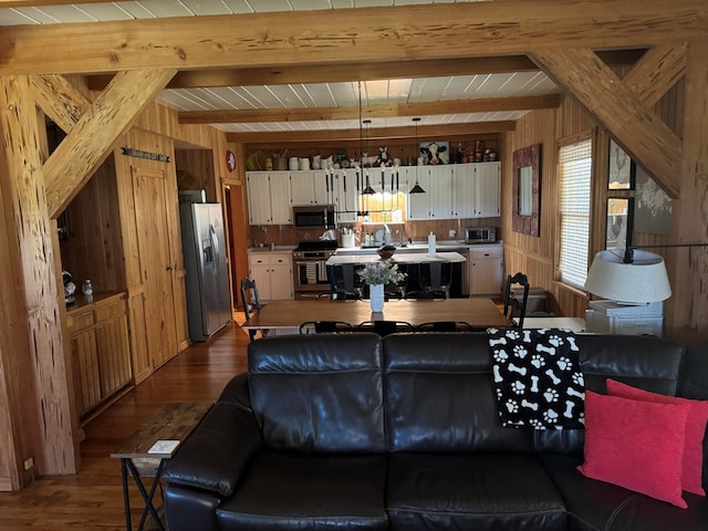 living room with beamed ceiling, dark wood-style flooring, and wood walls