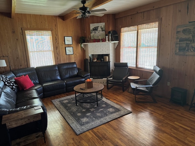 living area featuring beam ceiling, a brick fireplace, ceiling fan, and hardwood / wood-style floors