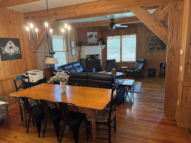 dining room featuring beamed ceiling, wooden walls, and hardwood / wood-style flooring